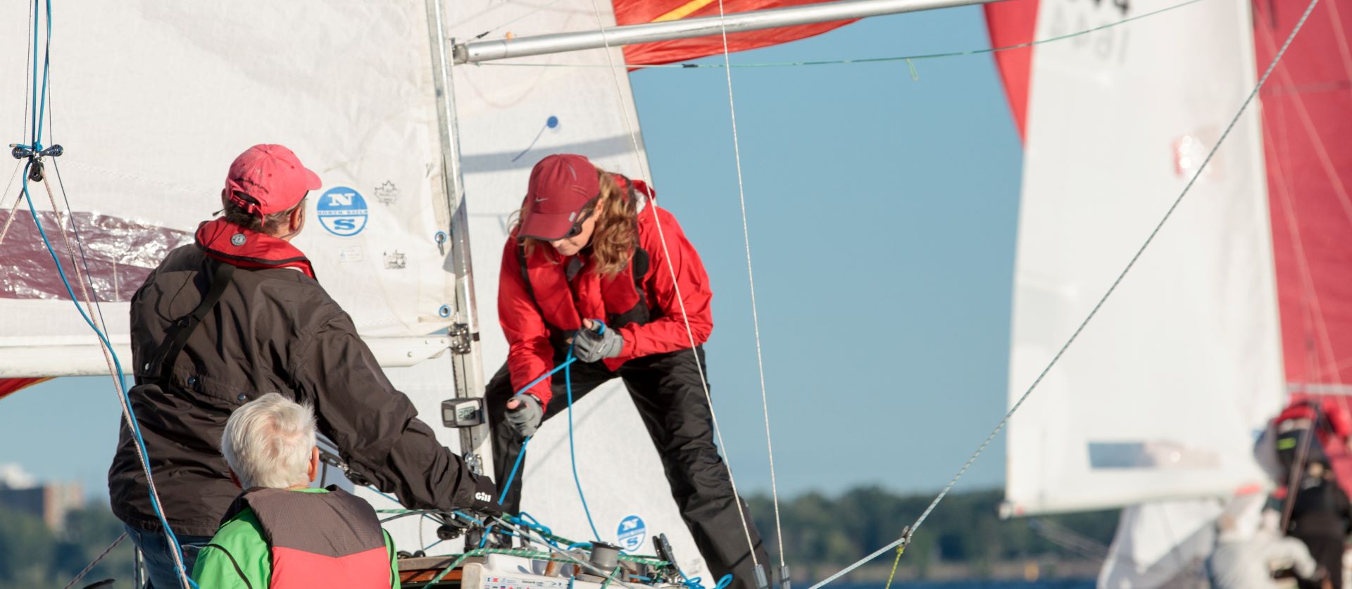 Three crew members work on rigging