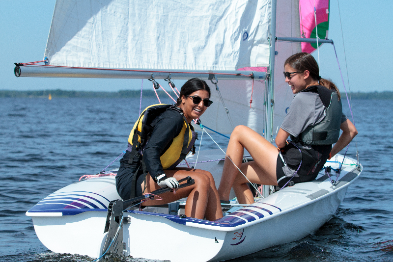 Two girls having fun learning how to sail a dinghy.