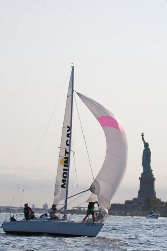 A J-24 sailboat sails past the Statue of Liberty