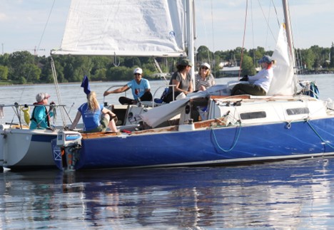 Two sailboats tied together with women crew socializing