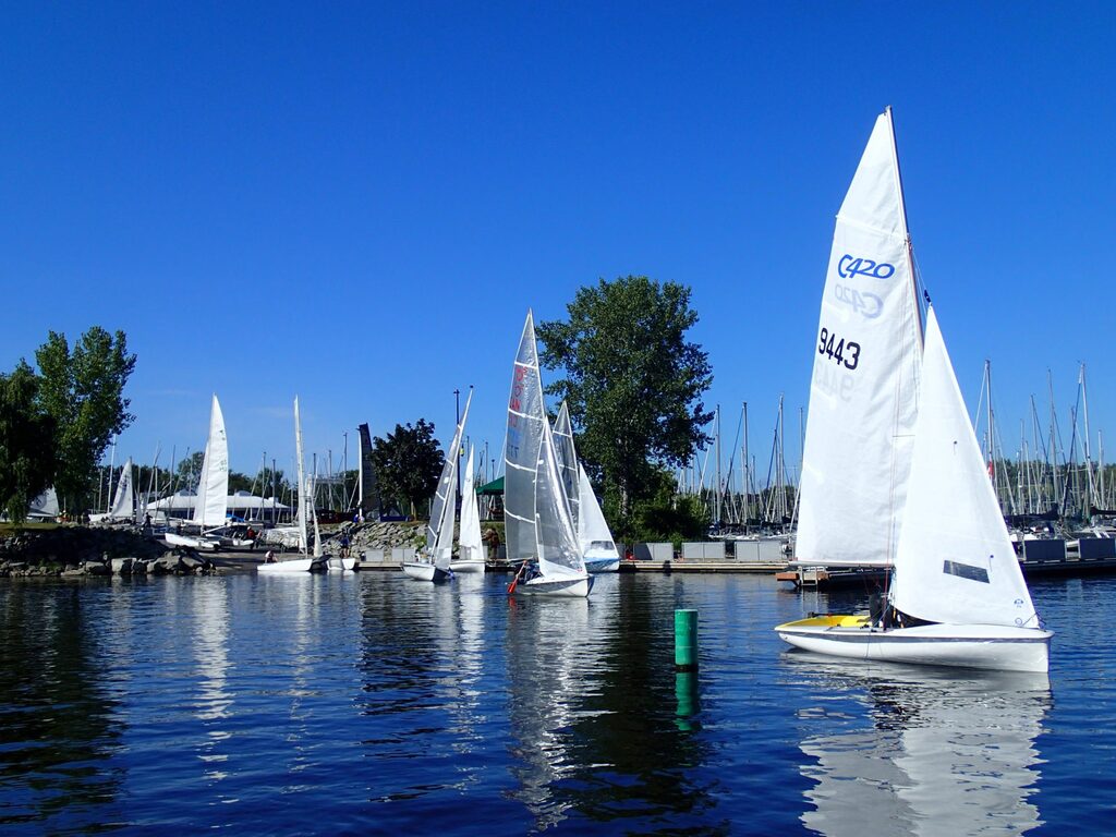 Dinghys leave the harbour under paddle with no wind