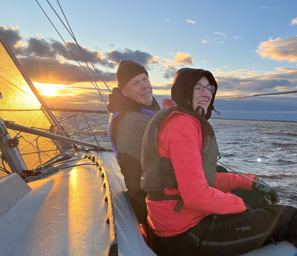 Two crew hang their legs over the side of a boat to reduce the heel.