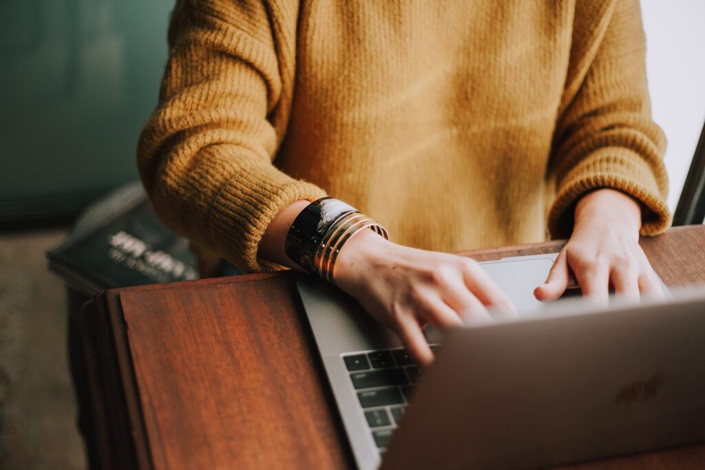 Shoulders and arms view of a person typing on a laptop.